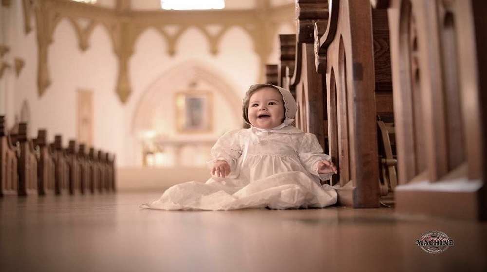 baby girl in a white christening gown inside a church