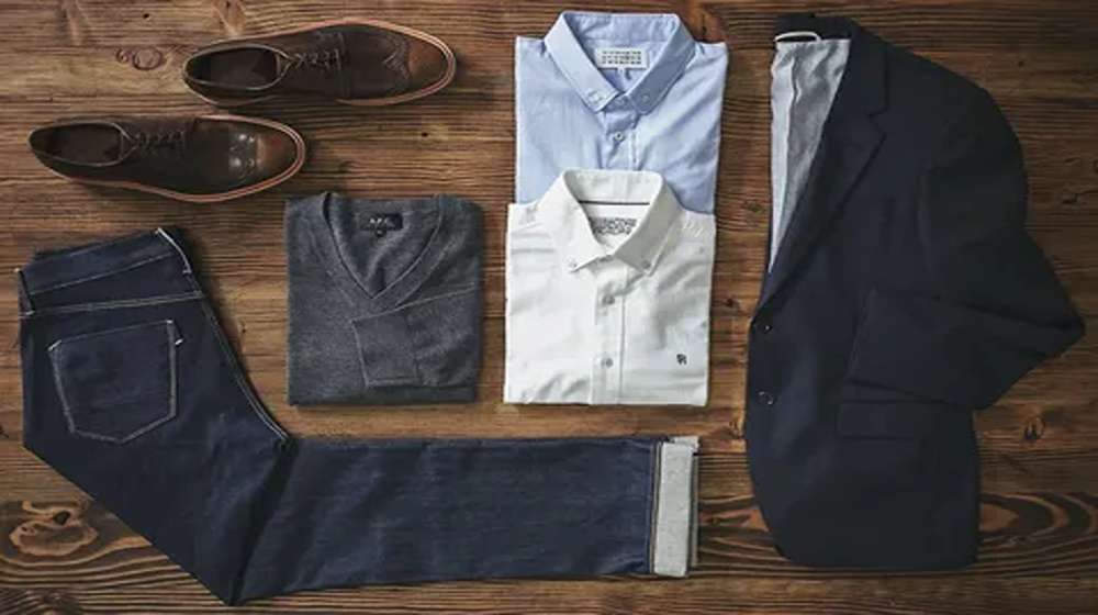 Flat lay of 15 wardrobe essentials for guys: shirts, trousers, knit and shoes